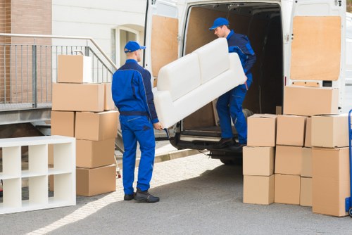 Two movers loading household items into a van during a moving service