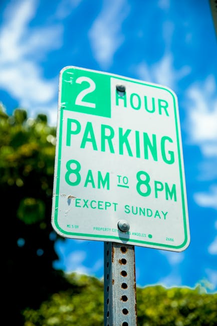 A close-up view of a green and white parking permit sign mounted on a metal post, indicating a two-hour parking restriction from 8 am to 8 pm, Monday to Saturday, with a note that it is not in effect 